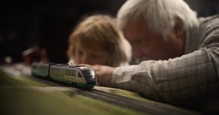 Grandfather showing granddaughter a model of a train